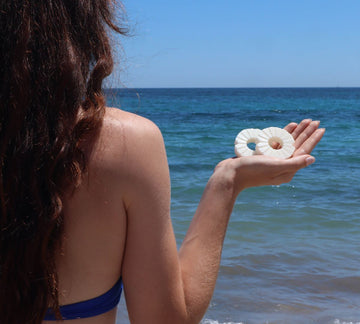 Vrouw houdt Lesseau blokzepen vast met helder blauwe zee als achtergrond